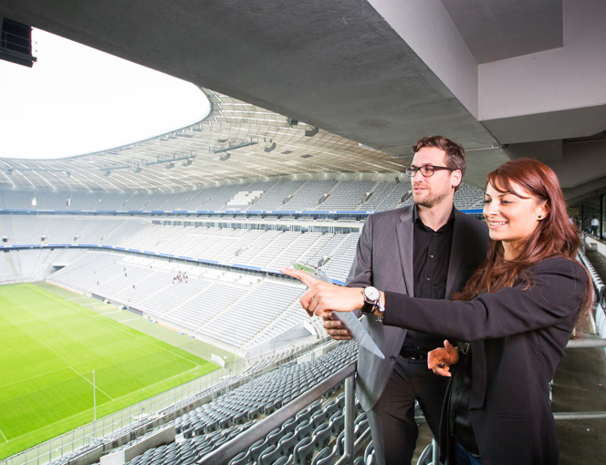 Tugba Coskun und ein Kunde stehen auf der Tribüne der Allianz Arena.