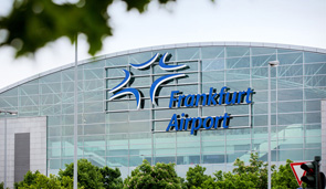 Außenansicht eines Flughafen-Gebäudes, an dessen Glasfassade das Logo „Frankfurt Airport“ zu sehen ist.